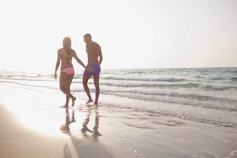 Ein Paar spaziert Händchen haltend am Strand
