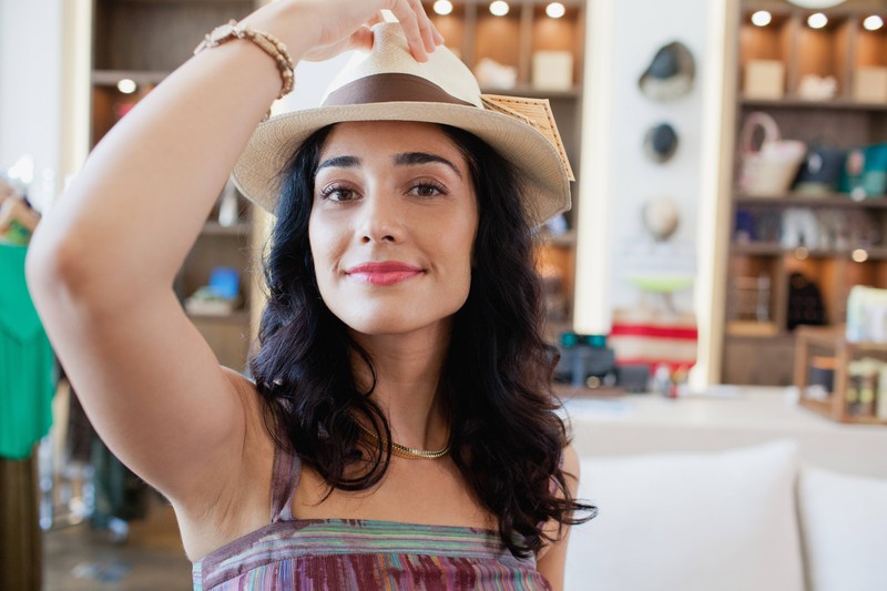 Eine junge Frau setzt einen Hut auf