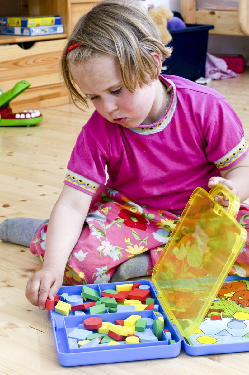 Ein kleines Mädchen sitzt im Kinderzimmer und spielt mit alten Spielsachen, die heute viel wert sein könnten