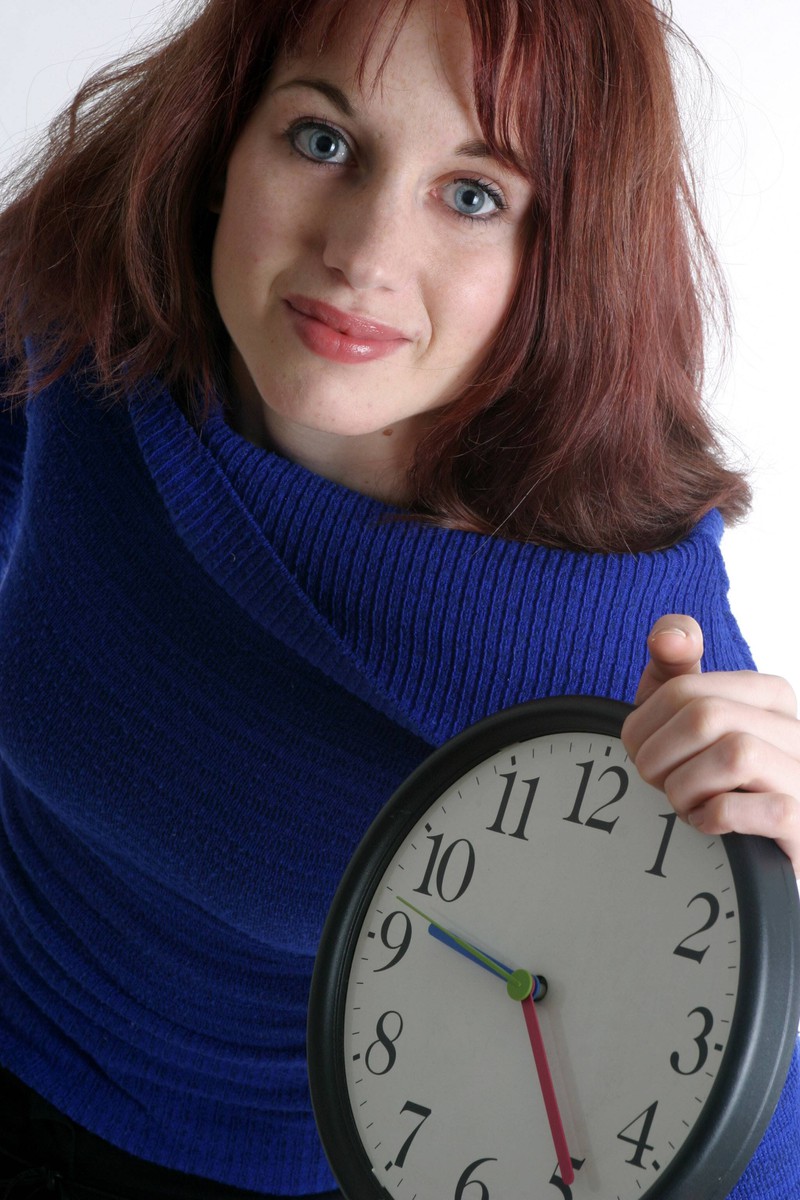 Eine Frau zeigt eine Uhr, auf der es halb 10 ist